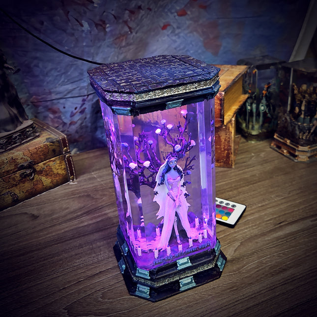 Futuristic figurine in a glowing purple display case on a wooden surface.