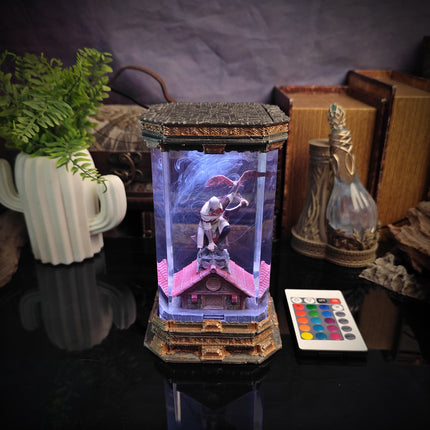 Decorative light box with figurines and colorful LED lights on a reflective surface.
