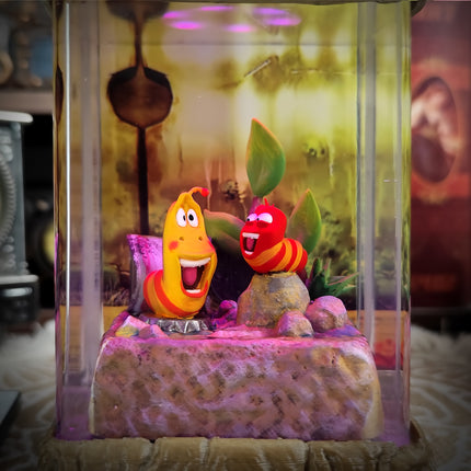 Two animated characters in a glass display case with a colorful background