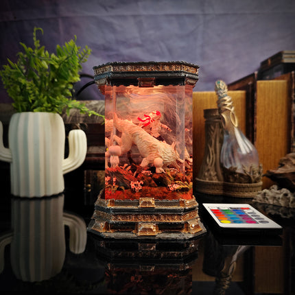 Decorative lamp with figurines and plants on a reflective surface