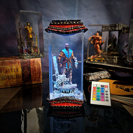 Light-up figurine in a transparent display case with remote control on a reflective surface.